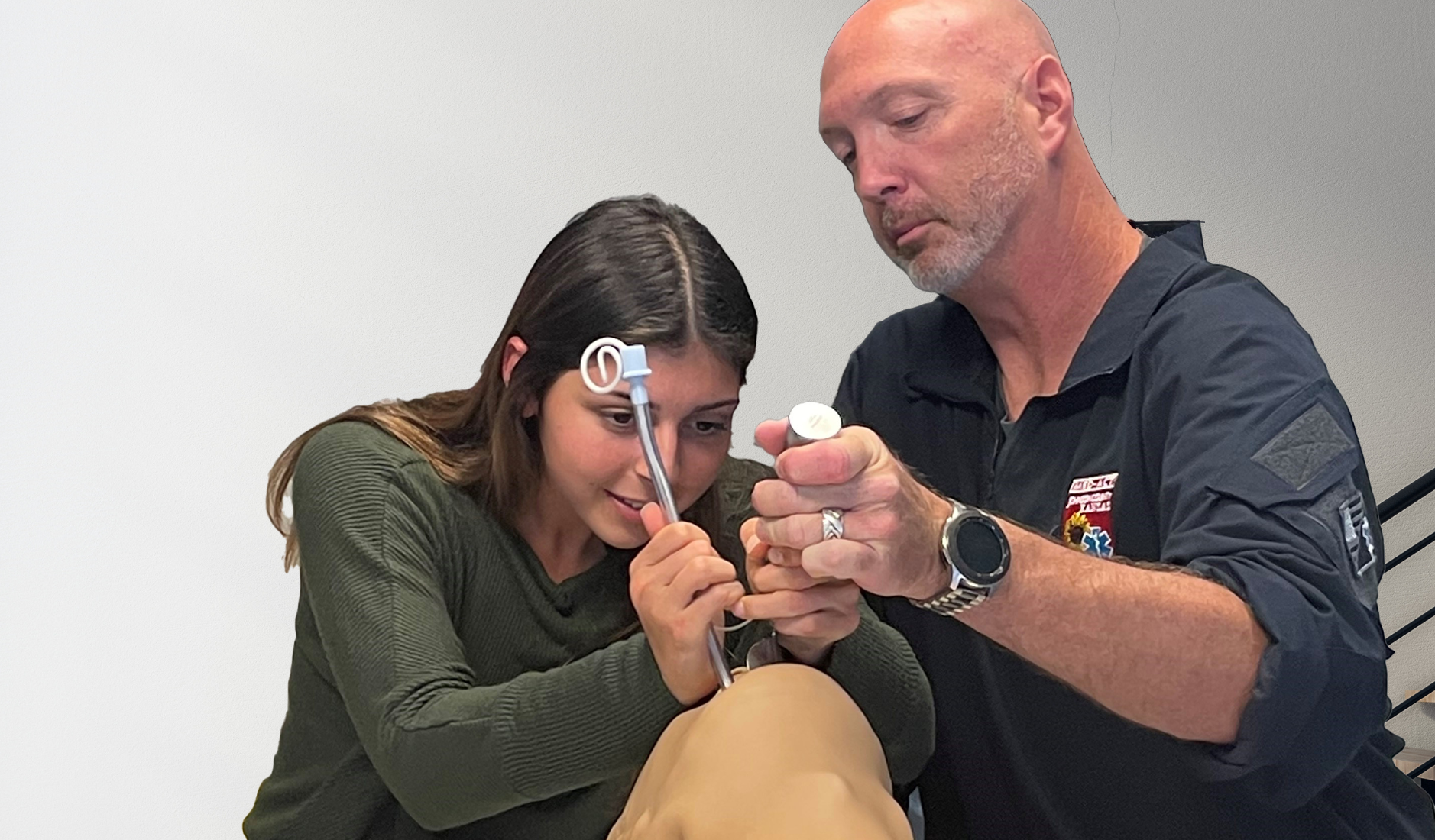 Professional EMT showing student how to intubate a patient.